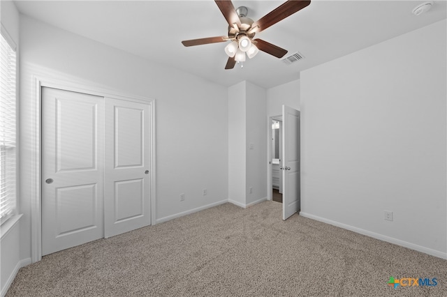 unfurnished bedroom with a closet, light colored carpet, and ceiling fan