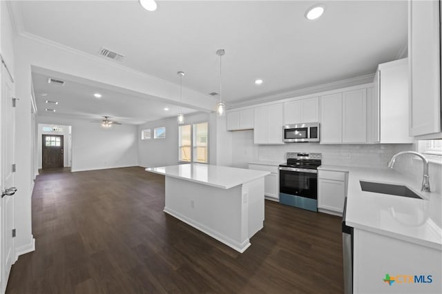 619 Killam Dr, Temple, TX 76502 - kitchen with stainless steel appliances, a sink, ornamental molding, white cabinets, and recessed lighting
