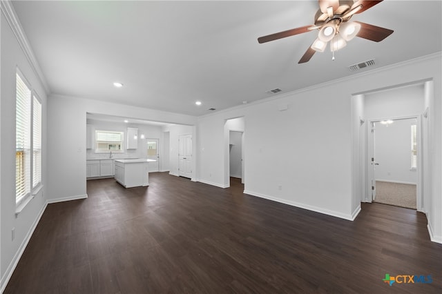 unfurnished living room featuring ceiling fan, a healthy amount of sunlight, and dark hardwood / wood-style flooring