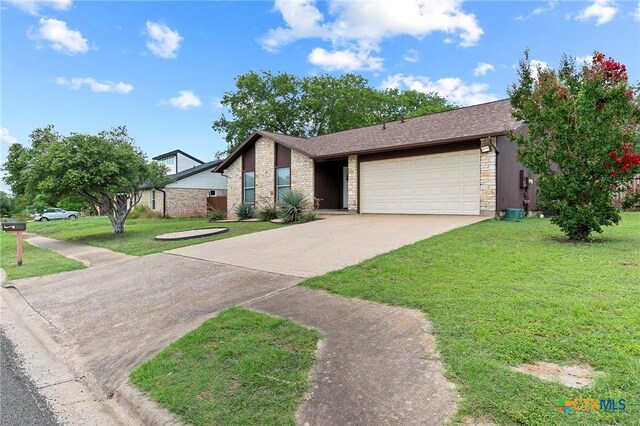 907 Great Oaks Cv, Round Rock, TX 78681 - mid-century home with stone siding, a garage, driveway, and a front lawn
