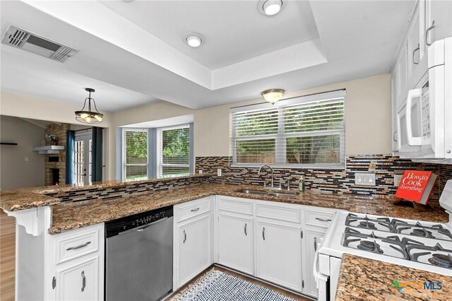 907 Great Oaks Cv, Round Rock, TX 78681 - kitchen with white appliances, a peninsula, decorative backsplash, white cabinetry, and dark stone countertops