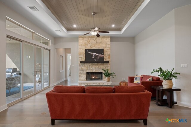 916 Dream Catcher Dr, Leander, TX 78641 - living area featuring a tray ceiling, wood finished floors, a ceiling fan, a stone fireplace, and wood ceiling