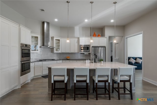 916 Dream Catcher Dr, Leander, TX 78641 - kitchen featuring appliances with stainless steel finishes, wall chimney exhaust hood, backsplash, white cabinetry, and a spacious island