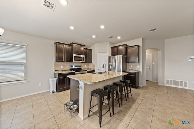 kitchen featuring stainless steel appliances, sink, tasteful backsplash, a breakfast bar area, and an island with sink