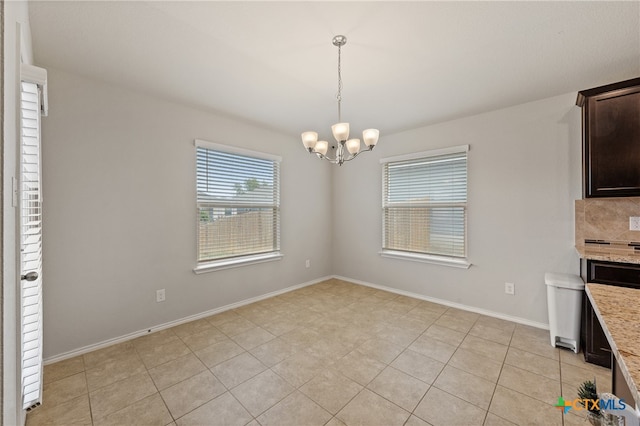 unfurnished dining area featuring light tile patterned flooring and an inviting chandelier