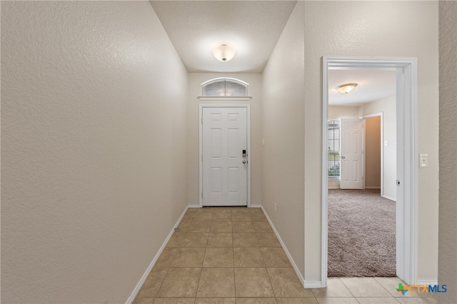 doorway with a textured ceiling and light carpet