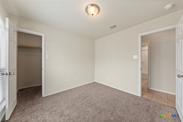 unfurnished bedroom featuring a closet, a spacious closet, and carpet