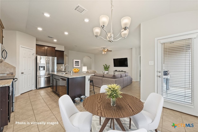 tiled dining area featuring ceiling fan with notable chandelier and sink