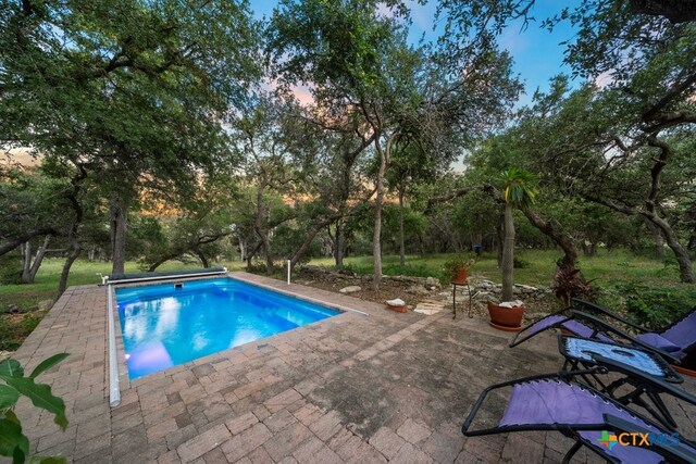 pool at dusk with a patio area