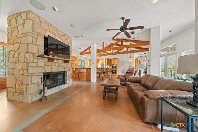 living room featuring beam ceiling, a wealth of natural light, ceiling fan, and a fireplace