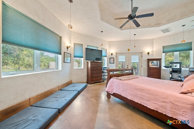 bedroom with a tray ceiling, multiple windows, french doors, and ceiling fan