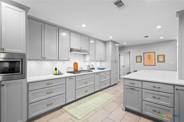 407 Pasadena Dr, Victoria, TX 77904 - kitchen featuring gray cabinets, stainless steel appliances, under cabinet range hood, backsplash, and light countertops