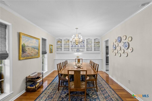 407 Pasadena Dr, Victoria, TX 77904 - dining room featuring dark wood-style floors, a chandelier, built in features, baseboards, and crown molding