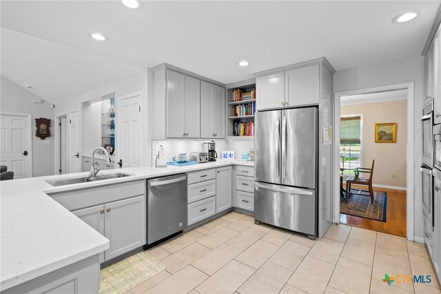 407 Pasadena Dr, Victoria, TX 77904 - kitchen featuring stainless steel appliances, a sink, open shelves, tasteful backsplash, and gray cabinetry