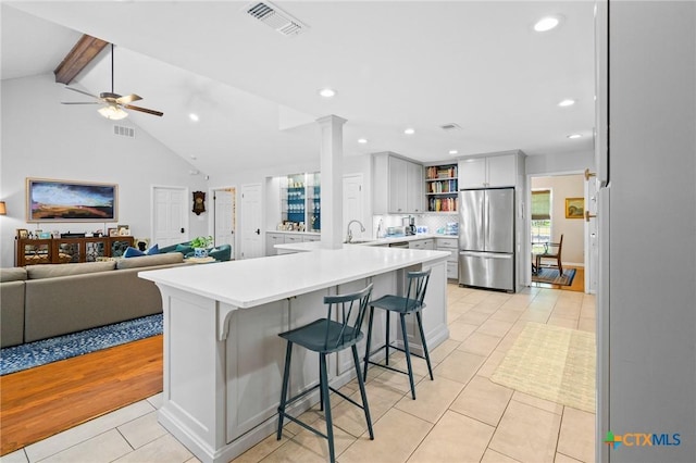407 Pasadena Dr, Victoria, TX 77904 - kitchen featuring freestanding refrigerator, open shelves, a peninsula, light tile patterned floors, and a breakfast bar