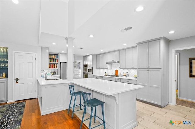 407 Pasadena Dr, Victoria, TX 77904 - kitchen with ornate columns, a peninsula, appliances with stainless steel finishes, light wood-type flooring, and light countertops