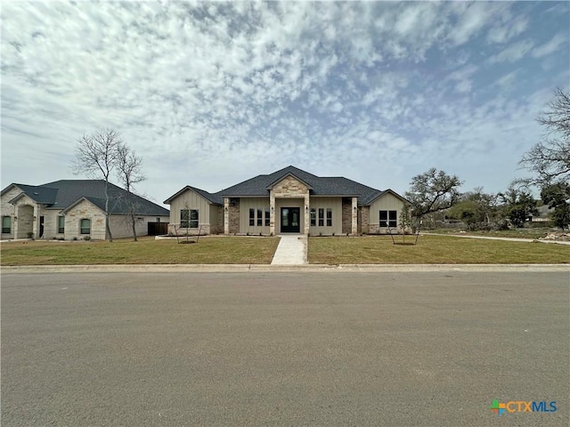 view of front of house featuring stone siding, a front lawn, and board and batten siding