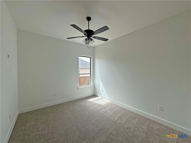 carpeted spare room featuring ceiling fan and baseboards