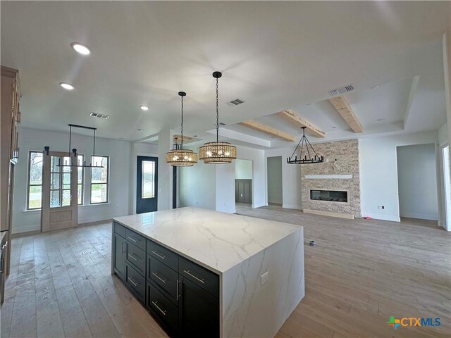 kitchen with light wood-style floors, a fireplace, and visible vents