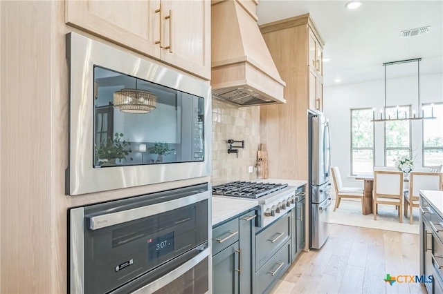 1586 Bosque Lago Dr, Belton, TX 76513 - kitchen with custom exhaust hood, stainless steel appliances, light wood-style flooring, tasteful backsplash, and a chandelier