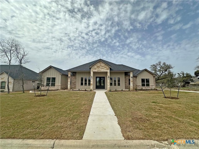 view of front of house with stone siding, a front lawn, board and batten siding, and french doors