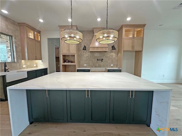 kitchen featuring recessed lighting, a sink, a large island, decorative backsplash, and custom range hood