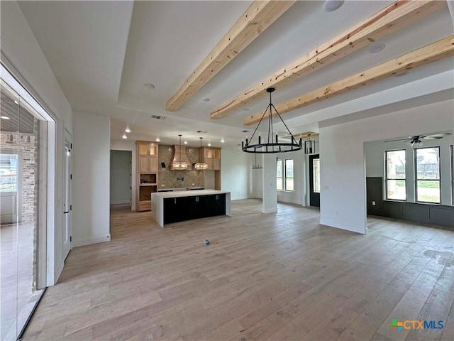 kitchen featuring open floor plan, light countertops, beamed ceiling, and light wood-style floors