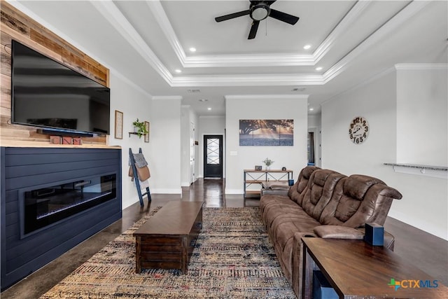 living room with a raised ceiling, ceiling fan, and ornamental molding