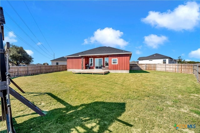 back of property with a lawn, an outbuilding, and a deck