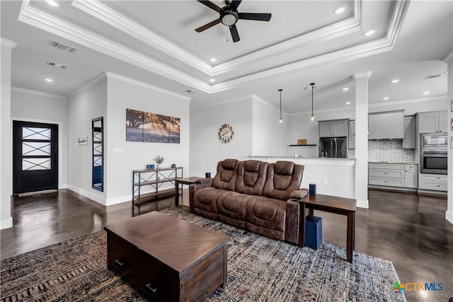 living room with a raised ceiling, ceiling fan, and ornamental molding