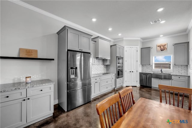 kitchen featuring sink, crown molding, gray cabinets, decorative backsplash, and appliances with stainless steel finishes