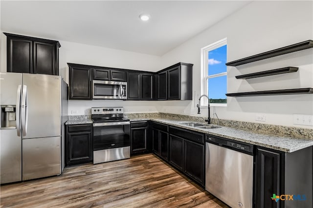 225 Rainey Dr Unit 73A, Jarrell, TX 76537 - kitchen with appliances with stainless steel finishes, a sink, dark cabinetry, light stone counters, and open shelves
