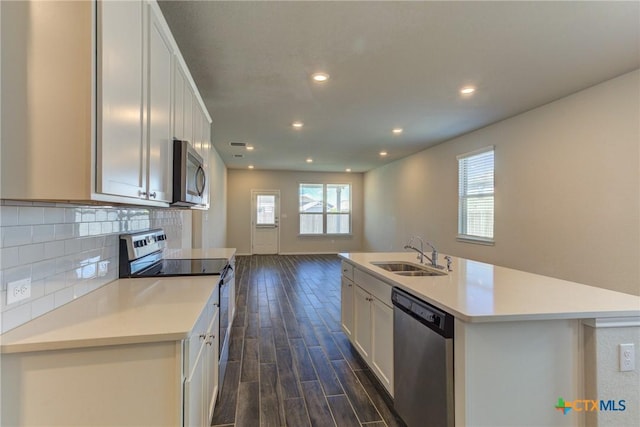 2420 Dielman Dr, Seguin, TX 78155 - kitchen featuring appliances with stainless steel finishes, a sink, dark wood-type flooring, white cabinetry, and light countertops
