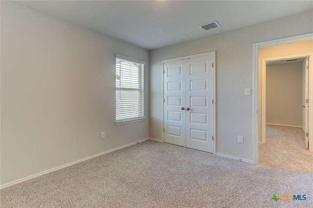 unfurnished bedroom featuring light carpet and a closet