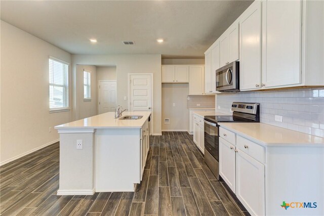 2420 Dielman Dr, Seguin, TX 78155 - kitchen with appliances with stainless steel finishes, dark wood-style floors, a sink, white cabinets, and recessed lighting
