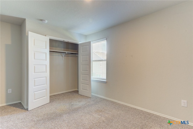 unfurnished bedroom featuring a closet and light colored carpet