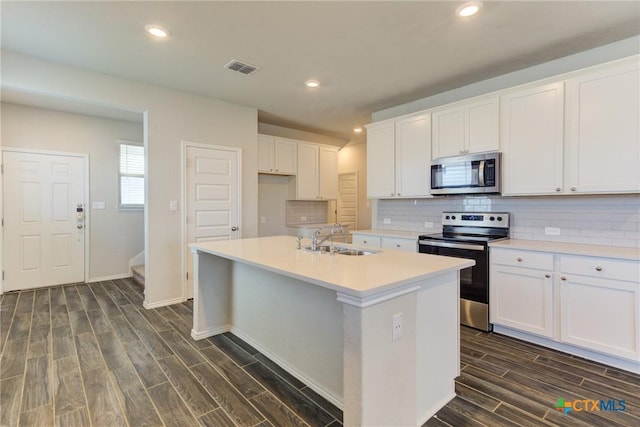 2420 Dielman Dr, Seguin, TX 78155 - kitchen featuring stainless steel appliances, a sink, dark wood-style flooring, a kitchen island with sink, and white cabinets