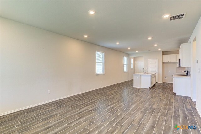2420 Dielman Dr, Seguin, TX 78155 - unfurnished living room featuring dark wood-type flooring, a sink, recessed lighting, and baseboards