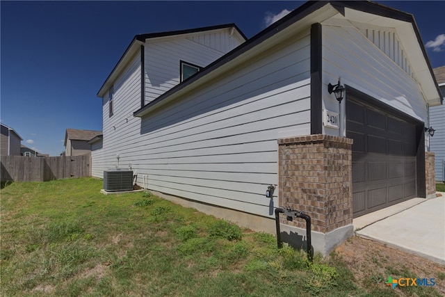 view of side of home featuring a garage, central AC, and a lawn