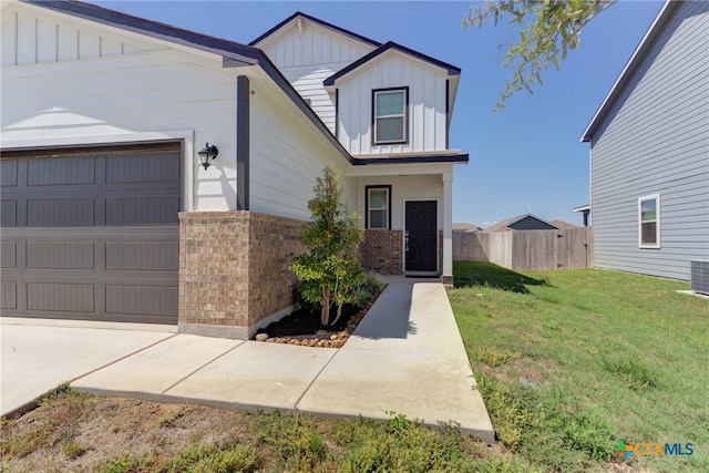 view of front facade with a garage, cooling unit, and a front lawn