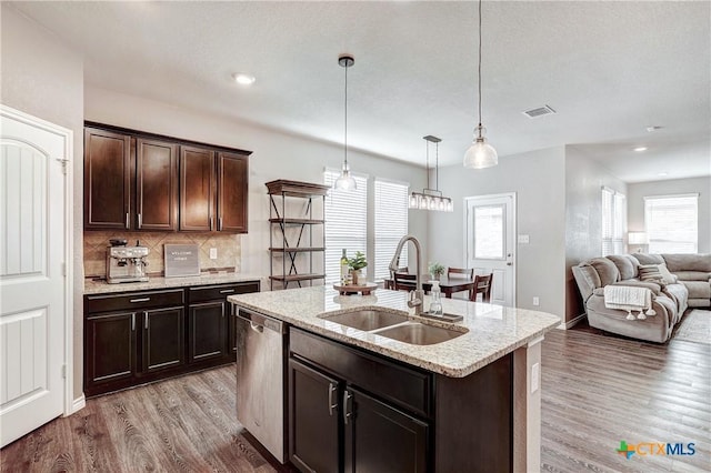 kitchen featuring backsplash, light wood-style flooring, dishwasher, and a sink