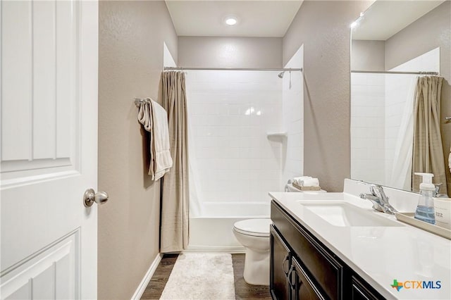 bathroom with shower / bath combo with shower curtain, toilet, wood finished floors, vanity, and a textured wall