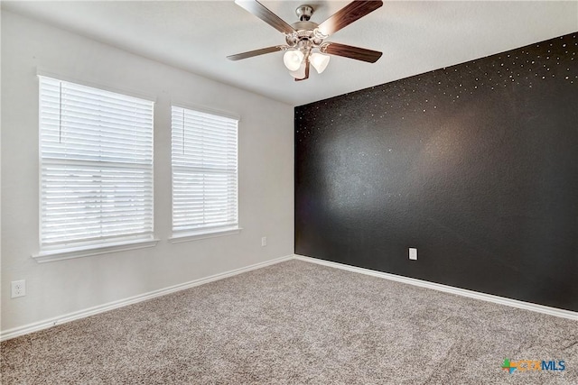 carpeted spare room with a healthy amount of sunlight, baseboards, and ceiling fan