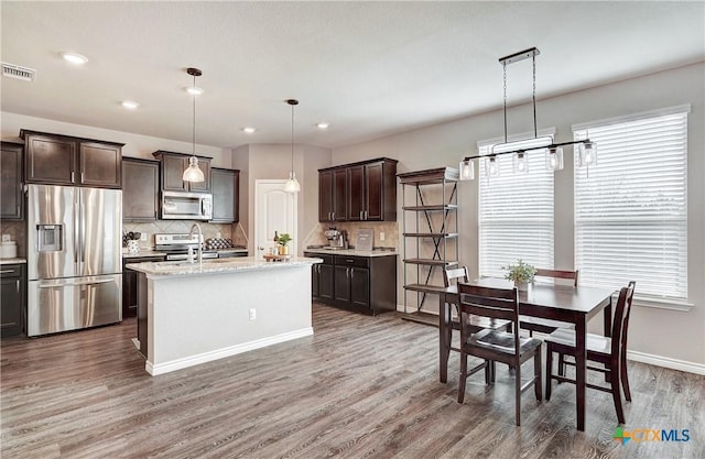 kitchen with visible vents, dark brown cabinets, wood finished floors, stainless steel appliances, and a sink