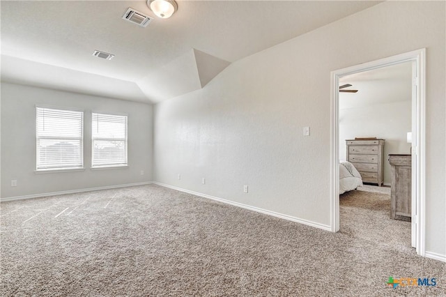 carpeted spare room with visible vents, baseboards, and lofted ceiling