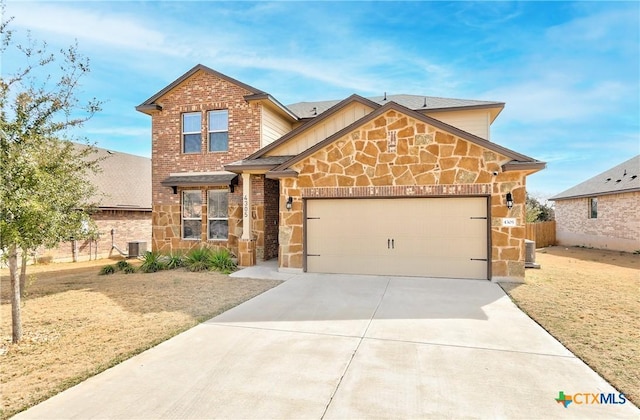 view of front of property featuring fence, central AC unit, driveway, an attached garage, and stone siding