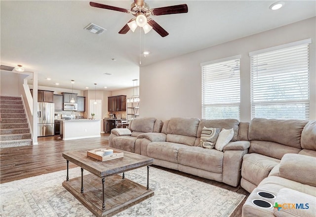 living room featuring recessed lighting, visible vents, wood finished floors, and stairs