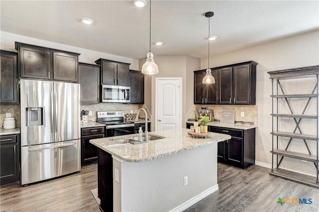 kitchen featuring light wood-style flooring, a sink, appliances with stainless steel finishes, light stone countertops, and dark brown cabinets