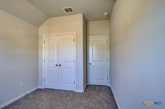 unfurnished bedroom featuring a closet, carpet floors, and lofted ceiling