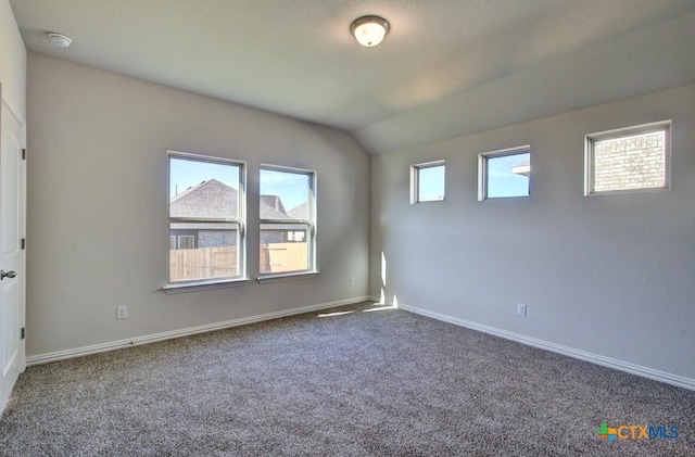 unfurnished room featuring dark colored carpet and lofted ceiling